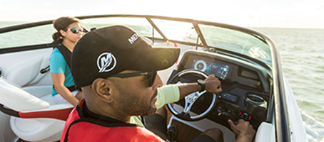 Man wearing Mercury Marine hat driving a boat