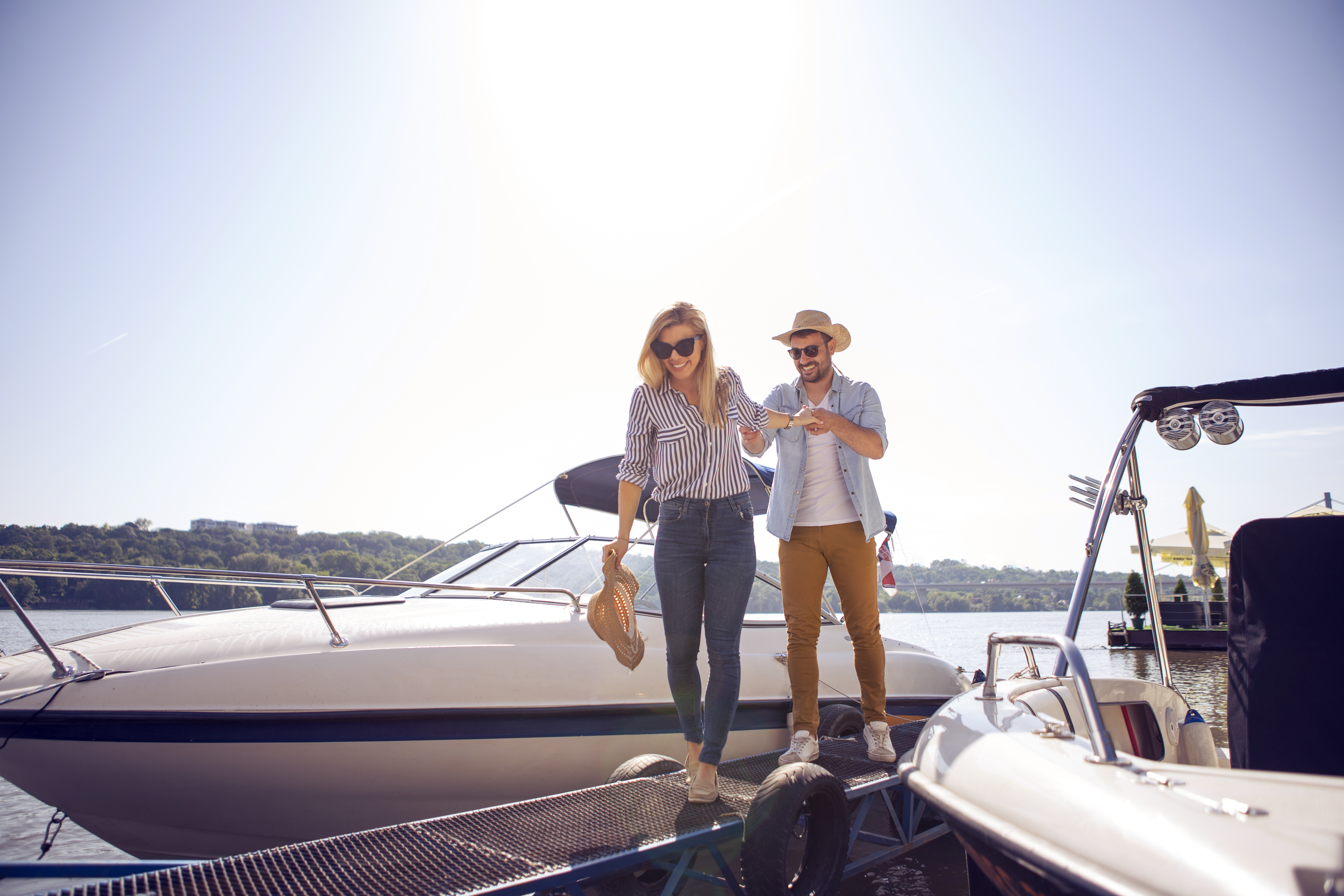 A couple stepping off their boat onto the dock on a sunny day. Docktober promotion now available for new boaters at select Maple Leaf Marina locations.