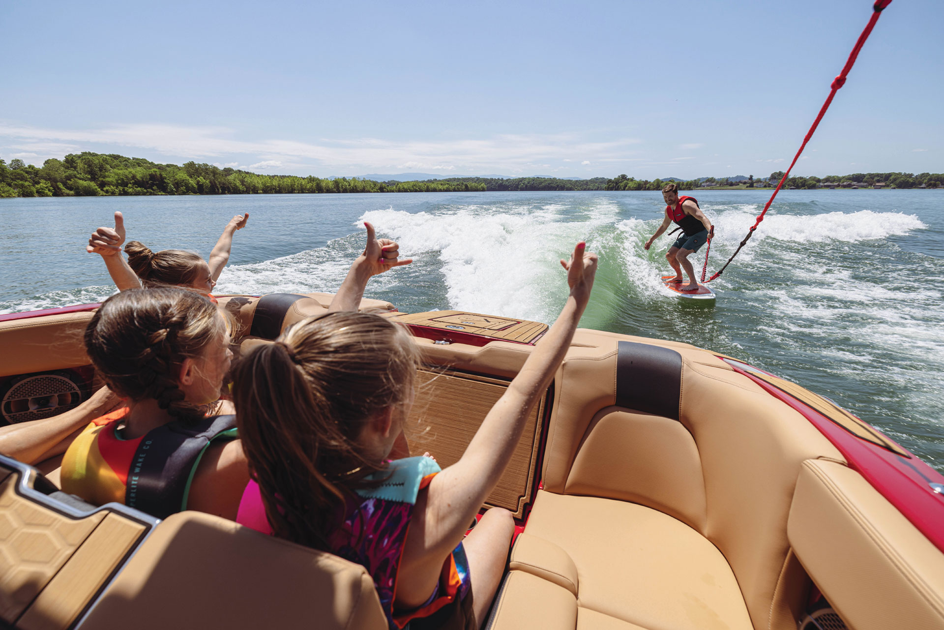 Kids cheering for make adult wake surfing behind a MasterCraft boat